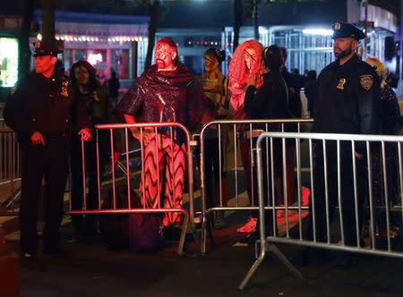 People in costume wait at a barricade with police officers for the New York City Halloween parade in New York City, U.S. October 31, 2017. REUTERS/Shannon Stapleton