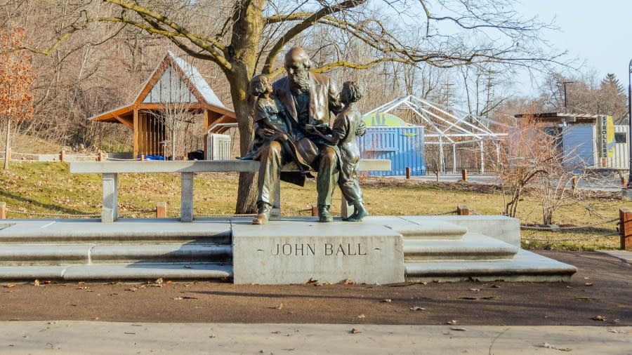 The John Ball statue, a bronze depiction of an elderly Ball visiting with two children, sits inside the entrance of the John Ball Zoo.