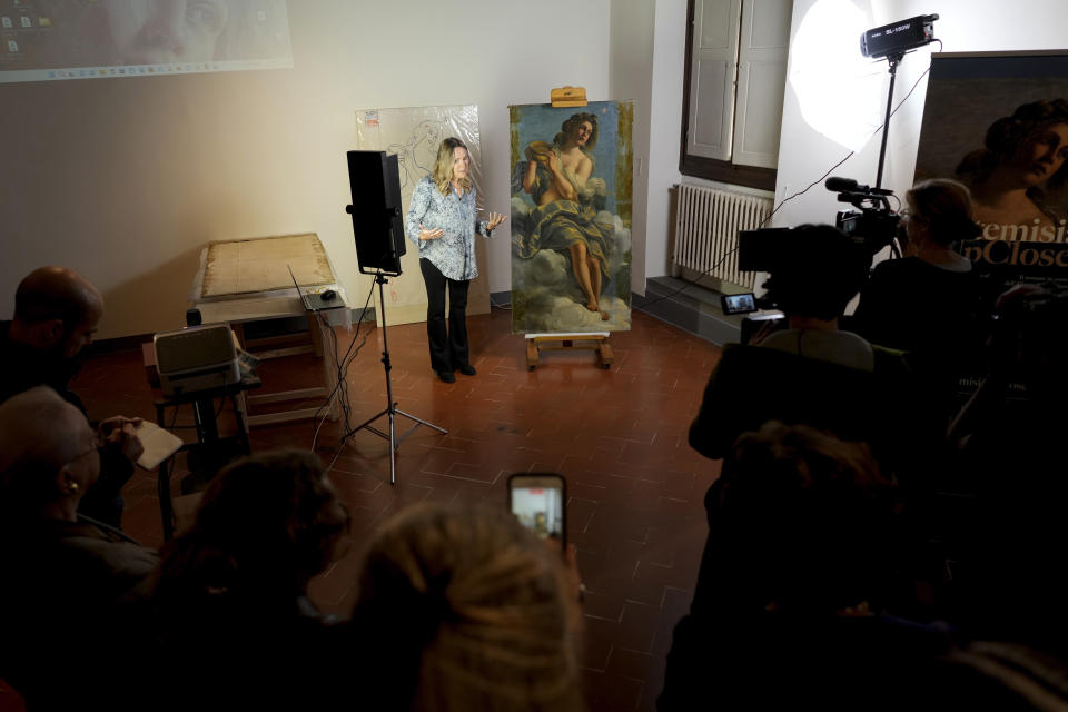 Restorer Elizabeth Wicks stands next to the "Allegory of Inclination", a 1616 work by Artemisia Gentileschi, during a press conference in the Casa Buonarroti Museum, in Florence, Italy, Wednesday, Nov. 9, 2022. Restorers have begun a six-month project on the "Allegory of Inclination" using modern techniques including x-rays and UV infrared research to go beneath the veils painted over the original to cover nudities and discover the work as Gentileschi painted it. (AP Photo/Andrew Medichini)