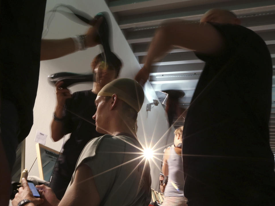 Hair stylists prepare a model prior to the start of the Vivienne Westwood men's Spring-Summer 2014 fashion collection, part of the Milan Fashion Week, unveiled in Milan, Italy, Sunday, June 23, 2013. (AP Photo/Luca Bruno)