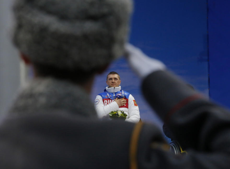 A Russian honor guard soldier salutes as Roman Petushkov of Russia, winner of the men's biathlon, 7.5km sitting event listens to the Russian national anthem during medal ceremony at the 2014 Winter Paralympic, Saturday, March 8, 2014, in Krasnaya Polyana, Russia. (AP Photo/Dmitry Lovetsky)