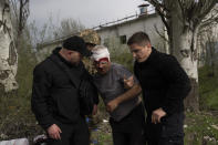 Member of security forces help an injured man following a Russian bombing of a factory in Kramatorsk, eastern Ukraine, Tuesday, April 19, 2022, killing at least one person and injuring three others. Russian forces attacked along a broad front in eastern Ukraine on Tuesday as part of a full-scale ground offensive to take control of the country's eastern industrial heartland in what Ukrainian officials called a "new phase of the war." (AP Photo/Petros Giannakouris)