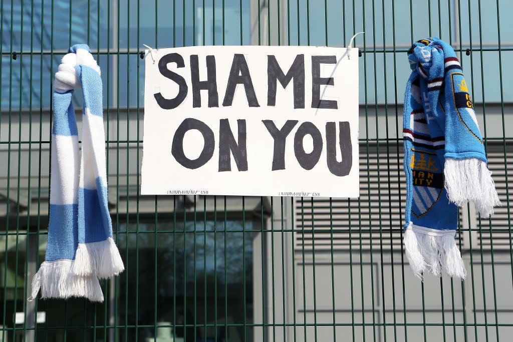 <p>Fans respond to announcement of a European Super League with Manchester City scarves outside the Etihad Stadium on 20 April</p> (Getty Images)
