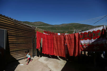 A girl runs outside her home near a section of the fence separating Mexico and the United States, on the outskirts of Tijuana, Mexico. REUTERS/Edgard Garrido