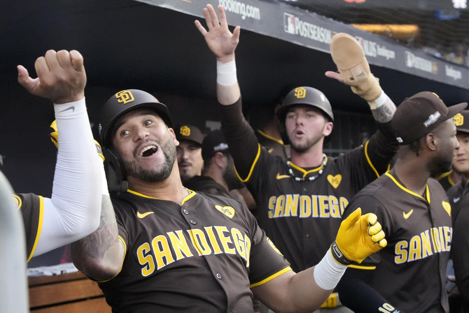 San Diego Padres' David Peralta, left, celebrates in the dugout after hitting a two-run home run that also scored Jackson Merrill, middle, during the second inning in Game 2 of a baseball NL Division Series against the Los Angeles Dodgers, Sunday, Oct. 6, 2024, in Los Angeles. (AP Photo/Mark J. Terrill)