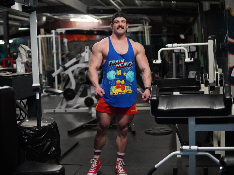 Carter Kissick, a heavily muscled bodybuilder, poses in a gym.