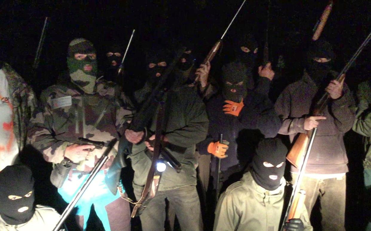This videograb made from a handout video shows alleged hooded hunters posing with rifles - AFP