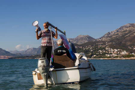 Environmental activist shouts slogans from a fishing boat during a protest against undersea oil exploration in the Adriatic Sea in Bar, Montenegro, November 14, 2018. REUTERS/Stevo Vasiljevic