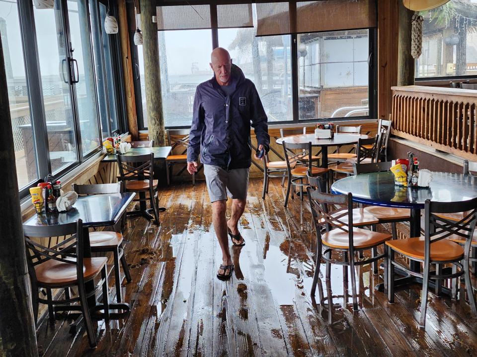 Grill owner Joe Penovich checks out the flooding that occurred inside his Port Canaveral restaurant Thursday morning after the passing of Hurricane Nicole. The restaurant is scheduled to reopen at 4 p.m. today.