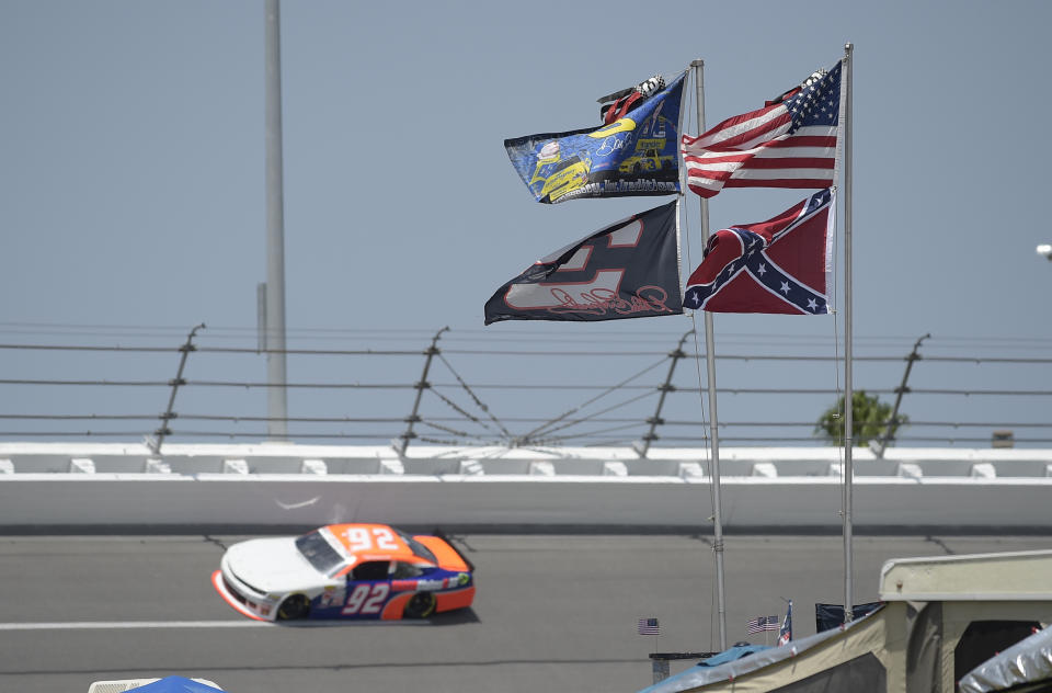 FILE - In this July 4, 2015, file photo, U.S., Confederate and Dale Earnhardt Sr. and Jr. flags fly near Turn 4 during NASCAR qualifying at Daytona International Speedway in Daytona Beach, Fla. NASCAR banned the Confederate flag from its races and venues Wednesday, June 10, 2020, formally severing itself from what for many is a symbol of slavery and racism. (AP Photo/Phelan M. Ebenhack, File)