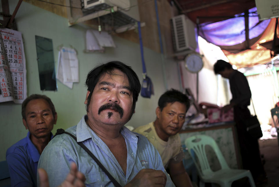 In this Tuesday, Aug. 13, 2013 photo, A Yaing Min, the "King of Cruelty," second left, and Phone Naing, second right, sit in their dimly lit office in downtown Yangon, Myanmar. Each morning, the bad guys of Yangon and their brethren - all members of Ko Lu Chaw, or "Handsome Guy Group," effectively a trade union for cinematic villains - arrive at dawn. They take up position at outdoor breakfast stalls along 35th and 36th streets, a tightly packed enclave of video production houses, movie-poster design studios and worse-for-wear apartment buildings that serves as the tattered ground zero of the Burmese movie industry. Hoping for day work, they order coffee or tea, and they hope. (AP Photo/Wong Maye-E)