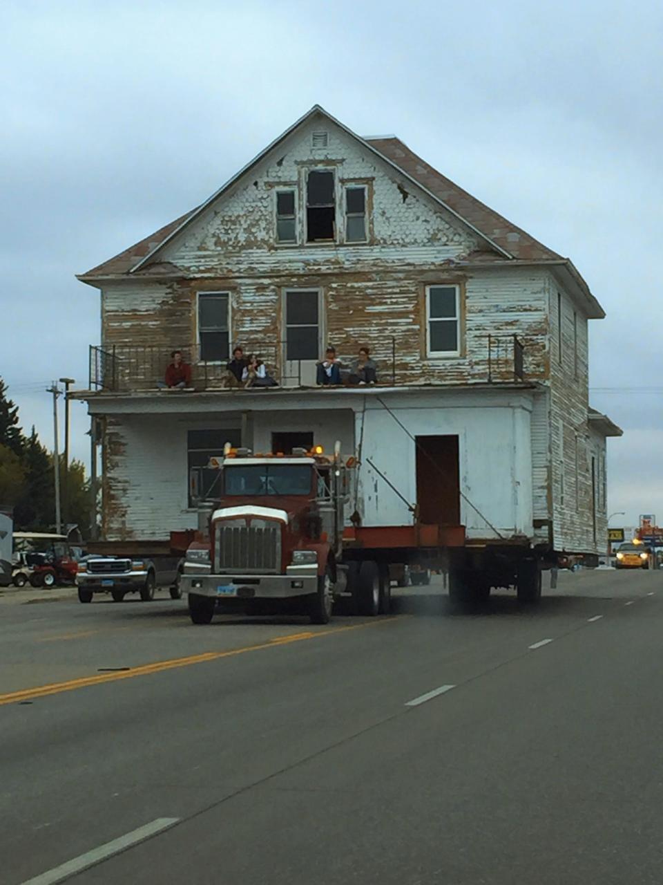 a two-story house, with attic, attached to a truck on the highway