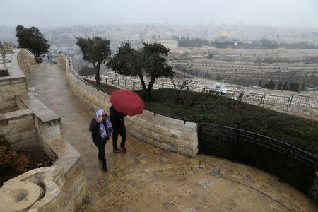 People walk with an umbrella as it rains at an observation point overlooking the Dome of the Rock and Jerusalem's Old City December 6, 2017. REUTERS/Ammar Awad