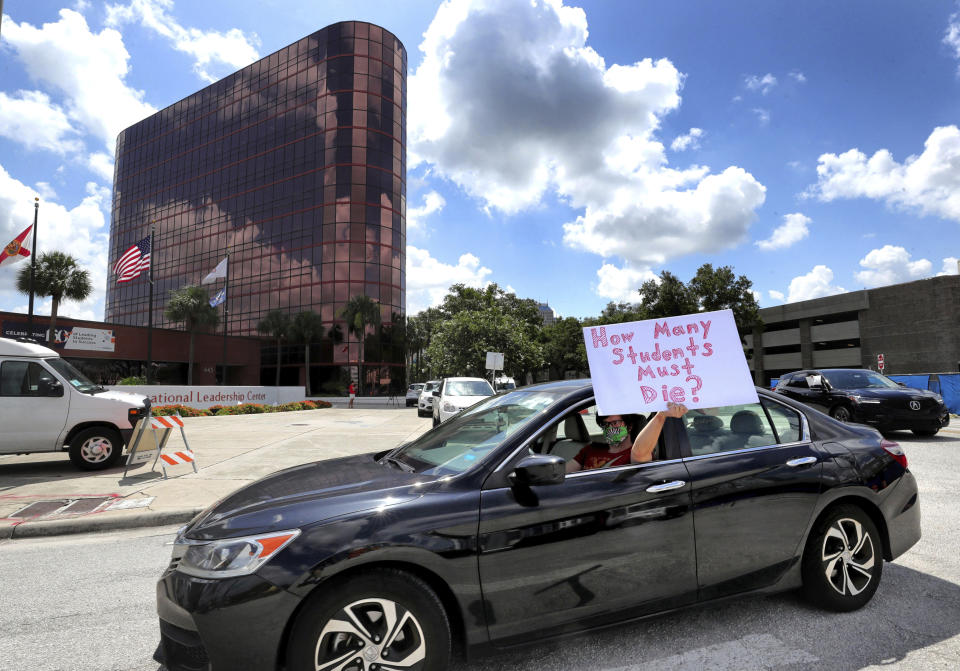 FILE - In this Tuesday, July 7, 2020 file photo, a teacher holds up a sign while driving by the Orange County Public Schools headquarters as educators protest in a car parade around the administration center in downtown Orlando, Fla. As pressure mounts for teachers to return to their classrooms this fall, concerns about the pandemic are pushing many toward alternatives, including career changes, as some mobilize to delay school reopenings in areas hardest hit by the coronavirus. Teachers unions have begun pushing back on what they see as unnecessarily aggressive timetables for reopening. (Joe Burbank/Orlando Sentinel via AP, File)