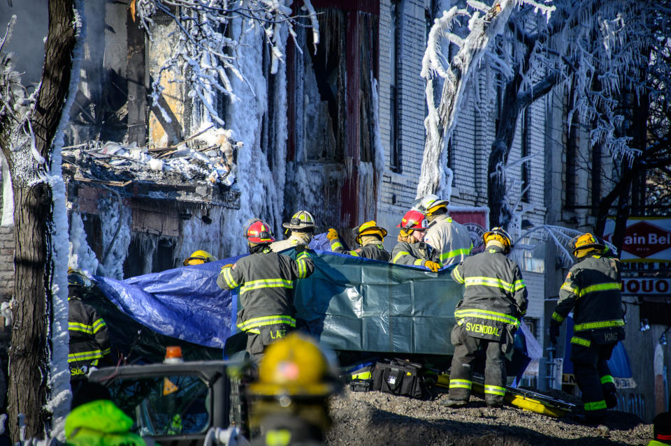 Investigators hold up a tarp as the body of a fire victim is removed, Thursday, Jan. 2, 2014 in Minneapolis. Authorities said Thursday they have discovered a body in the ruins of a Minneapolis apartment fire, as investigators were honing in on natural gas as a potential cause of the explosion and blaze that left 14 other people injured. (AP Photo/The Star Tribune, Glen Stubbe) MANDATORY CREDIT; ST. PAUL PIONEER PRESS OUT; MAGS OUT; TWIN CITIES TV OUT
