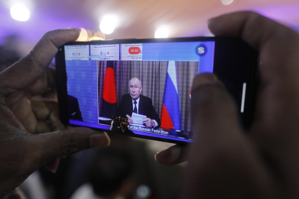 A man films on mobile phone as Russian President Vladimir Putin, attends through video conferencing the fuel handover ceremony of the Rooppur Nuclear Power Plant at Ishwardi in Pabna, Bangladesh, Thursday, Oct.5, 2023. (AP Photo/Mahmud Hossain Opu)
