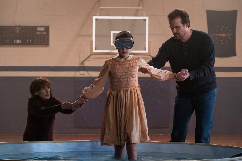 two adults helping eleven in a shallow pool