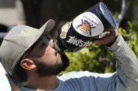 After finishing up an air conditioning repair call, Michael Villa, a service tech with Total Refrigeration, takes a drink of water as temperatures are expected to hit 117-degrees Wednesday, July 19, 2023, in Laveen, Ariz. (AP Photo/Ross D. Franklin)