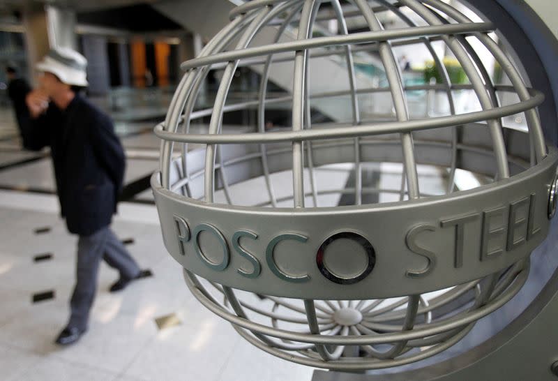 A man walks past a logo of POSCO at the company's headquarters in Seoul