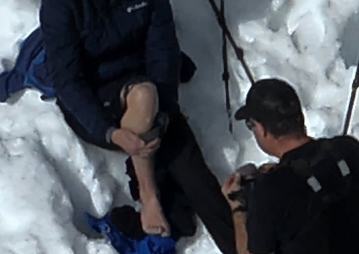 Rescuer helping shoeless hiker in snow