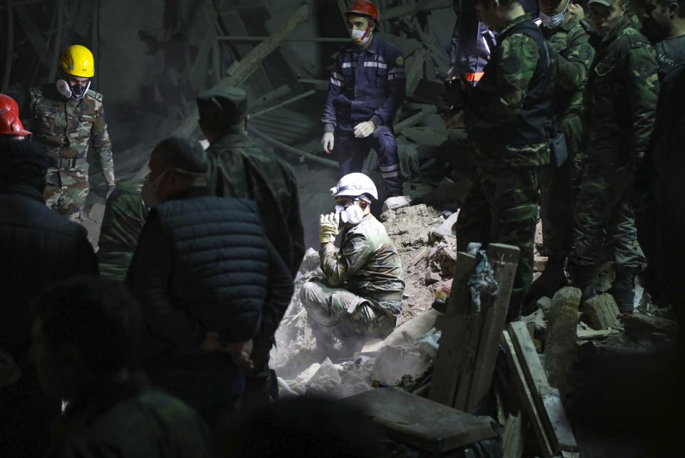 Soldiers and firefighters search for survivors in a residential area that was hit by rocket fire overnight by Armenian forces, early Saturday, Oct. 17, 2020, in Gyanga, Azerbaijan's second largest city, near the border with Armenia. (AP Photo/Aziz Karimov)