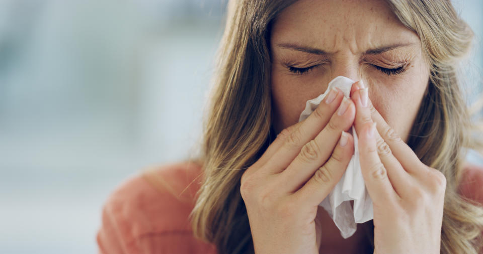 Woman blowing her nose with a tissue.