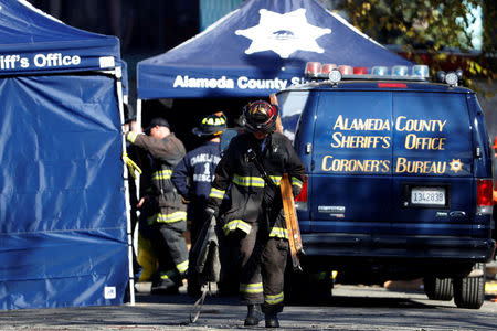 A firefighter carries equipment at the scene of a fire in the Fruitvale district of Oakland, California, U.S. December 4, 2016. REUTERS/Stephen Lam