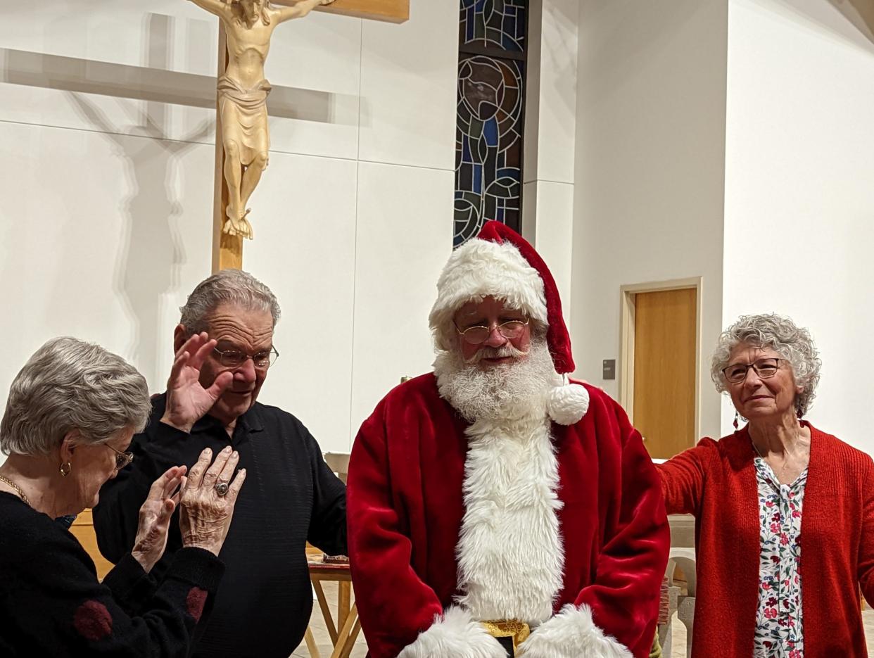 Santa's Helper Frank Kohring of Canton Township and his wife, Sally (right), accept prayers from members of the Community of Praise Charismatic Catholic Prayer Group, which meets at Walsh University. Kohring said he considers being a Santa's Helper as a ministry to share God's love.