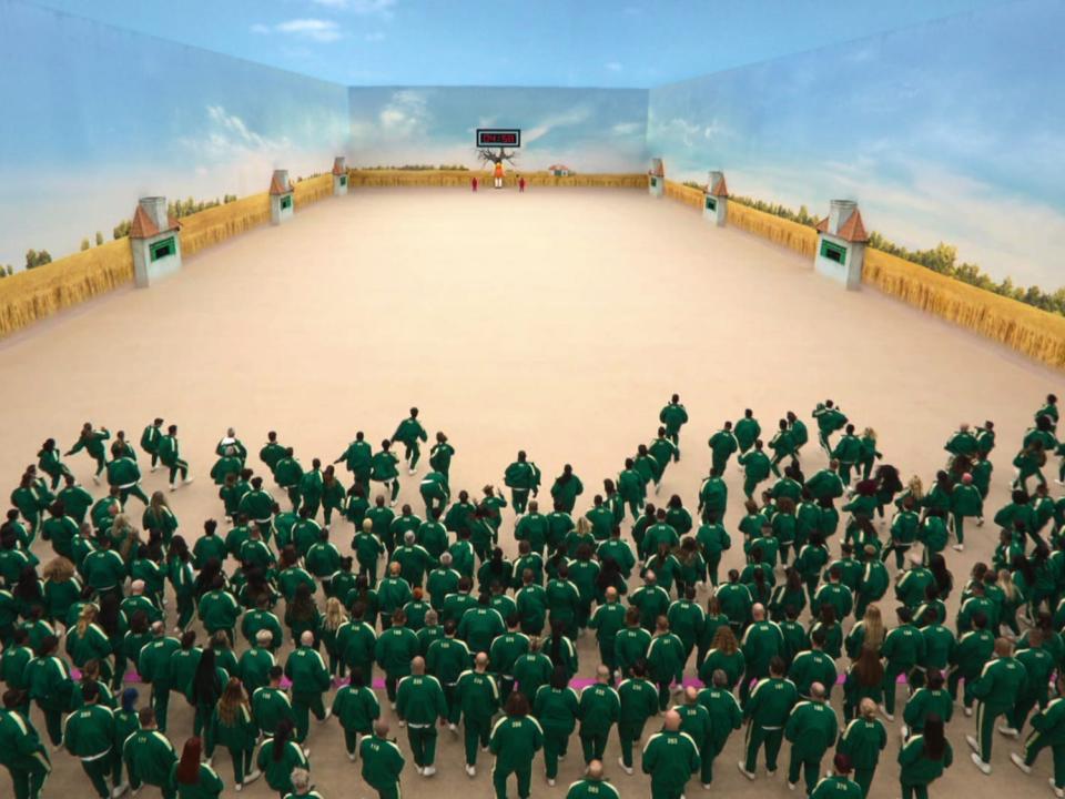 A crowd in green running across a room in "Squid Game: The Challenge"