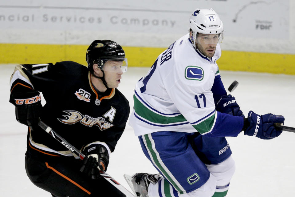 Anaheim Ducks' Saku Koivu, left, of Finland, and Vancouver Canucks' Ryan Kesler look at the puck during the first period of an NHL hockey game on Wednesday, Jan. 15, 2014, in Anaheim, Calif. (AP Photo/Jae C. Hong)