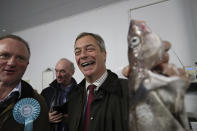 Brexit Party Leader Nigel Farage holds a fish during an event at the Grimsby Seafood Village, with local Brexit Party candidate Christopher Barker, left, part of the General Election campaign trail, in Grimsby, England, Thursday, Nov. 14, 2019. Britain goes to the poll on Dec. 12. (Danny Lawson/PA via AP)