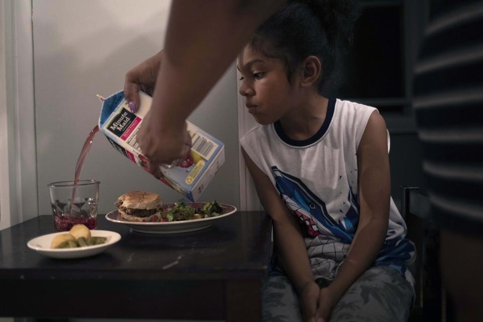 In this Thursday, Aug. 15, 2019, photo, Kathryn Gatewood pours juice into a glass for her son, Tracy at their home in Chicago's Englewood Neighborhood. "We spend almost 40% of our paychecks combined to ensure a healthier diet for our kids," she said, adding that it is a better alternative than buying bad food from the "dusty shelves" of corner stores in Englewood. (AP Photo/Amr Alfiky)