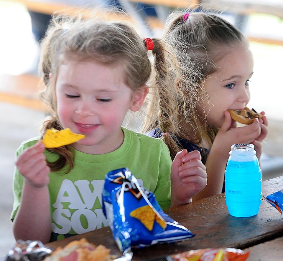 McKenzie Hammond, 4, left, and Kenzley Barringer, 4, enjoy snacks Monday, April 8, 2024, during The Total Solar Eclipse Watch Party at Butler Rodman Park in Alliance.
