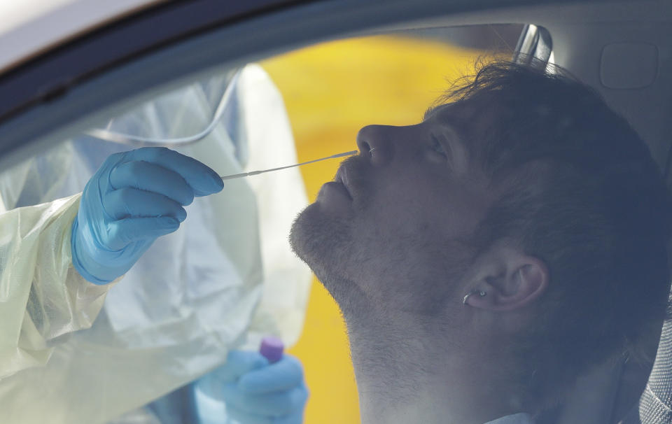 Medical staff take a COVID-19 test from a visitor to a drive through community based assessment centre in Christchurch, New Zealand, Thursday, Aug. 13, 2020. Health authorities in New Zealand are scrambling to trace the source of a new outbreak of the coronavirus as the nation's largest city, Auckland, goes back into lockdown. (AP Photo/Mark Baker)