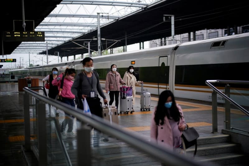Passengers wearing face masks travel with their belongings at a railway station in Xianning