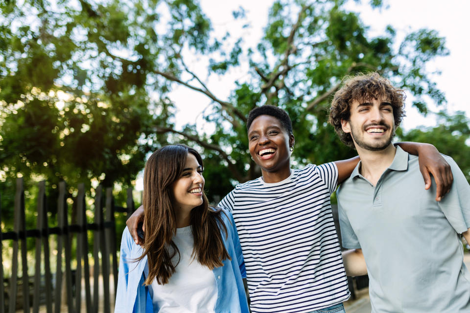 United multiracial friends having fun embracing and walking together outdoor