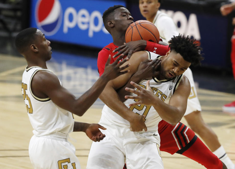 Utah center Lahat Thioune, back, wrestles away a rebound from Colorado forward Evan Battey, front right, as Colorado guard McKinley Wright IV, left, looks on in the first half of an NCAA college basketball game Sunday, Jan. 12, 2020, in Boulder, Colo. (AP Photo/David Zalubowski)