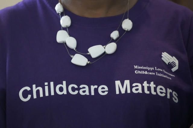 A staff member wearing a Mississippi Low Income Child Care Initiative t-shirt, listens as officials speak about a policy change by the Mississippi Department of Human Services, that removed a child support requirement for the Child Care Payment Program, at a news conference Monday, May 15, 2023, in Jackson, Miss. (AP Photo/Rogelio V. Solis)