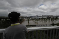 A man watches the flooded park near the Han River in Seoul, South Korea, Thursday, Aug. 6, 2020. The state-run Han River Flood Control Office issued a flood alert near a key river bridge in Seoul, the first such advisory since 2011. (AP Photo/Lee Jin-man)