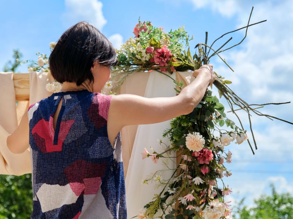 woman adding florals to a wedding arch