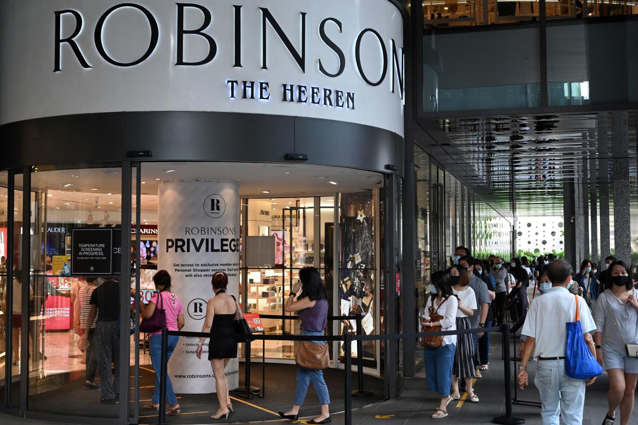 Customers queue to enter a Robinsons department store at the Hereen in the Orchard Road shopping belt in Singapore on October 30, 2020, after the company announced that it was closing its last two stores in the country due to falling demand as more consumers shift to online shopping. (Photo by Roslan RAHMAN / AFP) (Photo by ROSLAN RAHMAN/AFP via Getty Images)