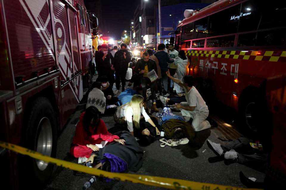 Injured people are helped at the street near the scene of a crowd surge in Seoul, South Korea, Sunday, Oct. 30, 2022. Witnesses say the nightmarish scene intensified as people performed CPR on the dying and carried limp bodies to ambulances, while dance music pulsed from garish clubs lit in bright neon. Others tried desperately to pull out those who were trapped underneath the crush of people, but failed because too many in the crowd had fallen on top of them. (AP Photo/Lee Jin-man)