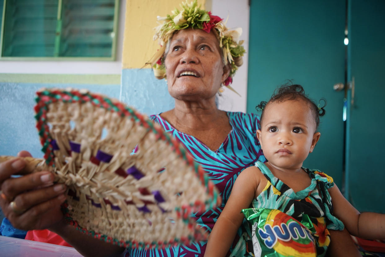 A woman and child watch as dancers perform 