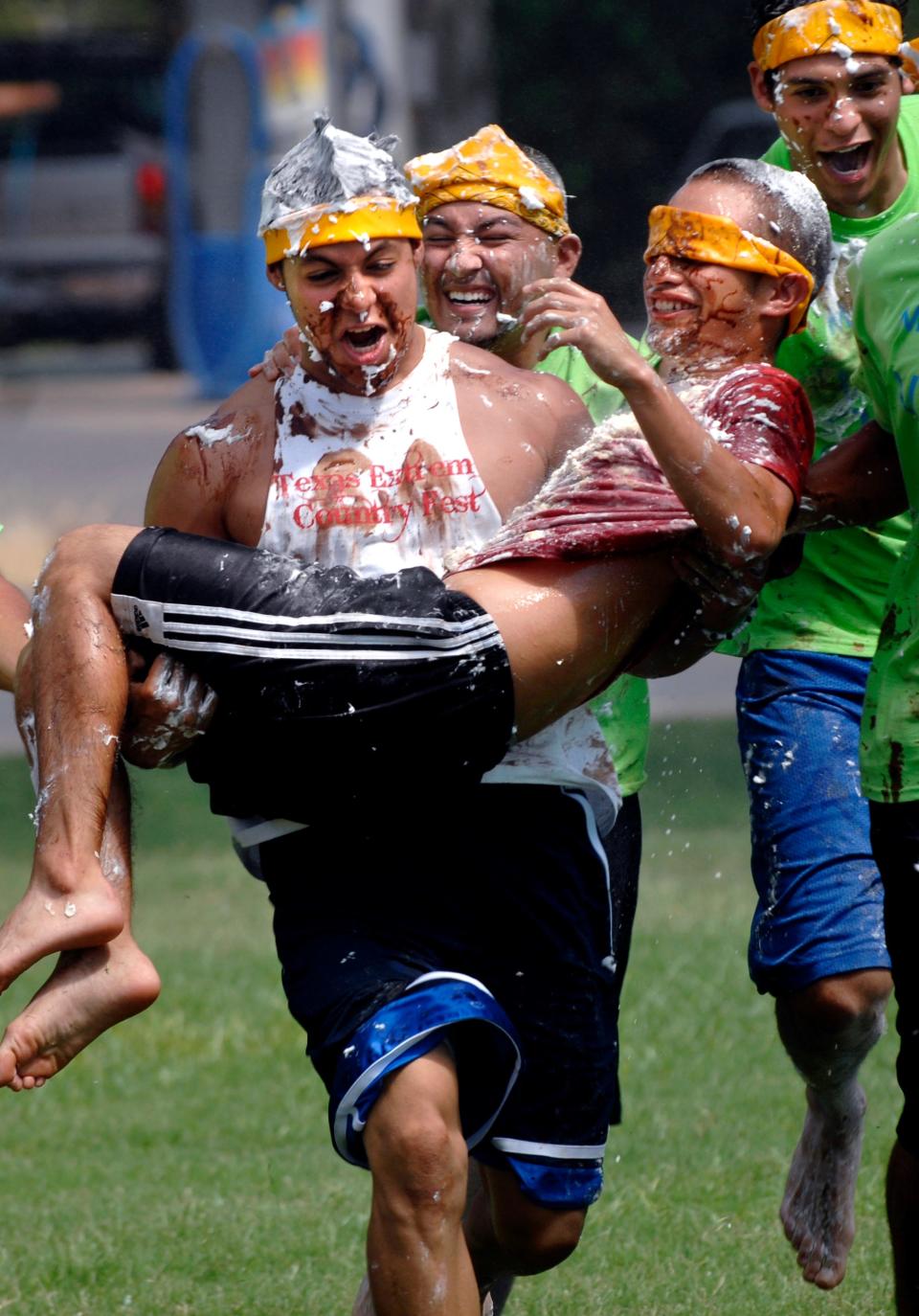 Rolando Mendoza of Wimberley carries Raul Castillo of Abilene during The Human Cake contest. His teammates covered Castillo in oil, eggs milk and flour and then carried him up and back across the field. McMurry University held its annual Slime Olympics in August 2010 as part of their incoming freshman orientation.