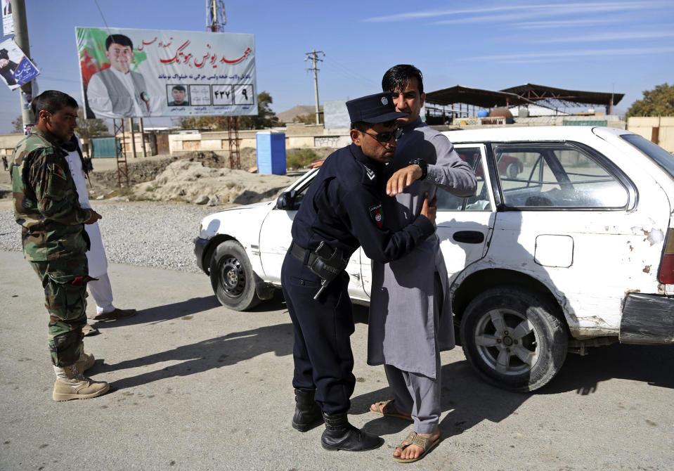 In this Wednesday Oct. 17, 2018 photo, an Afghan Policeman searches a man at a checkpoint ahead of parliamentary elections, in Kabul, Afghanistan. Afghans will go to the polls on Saturday, hoping to bring change to a corrupt government that has lost nearly half the country to the Taliban. On Thursday, three top provincial officials in the southern province of Kandahar were killed by their own guards during a meeting to discuss security ahead of the vote. (AP Photo/Rahmat Gul)