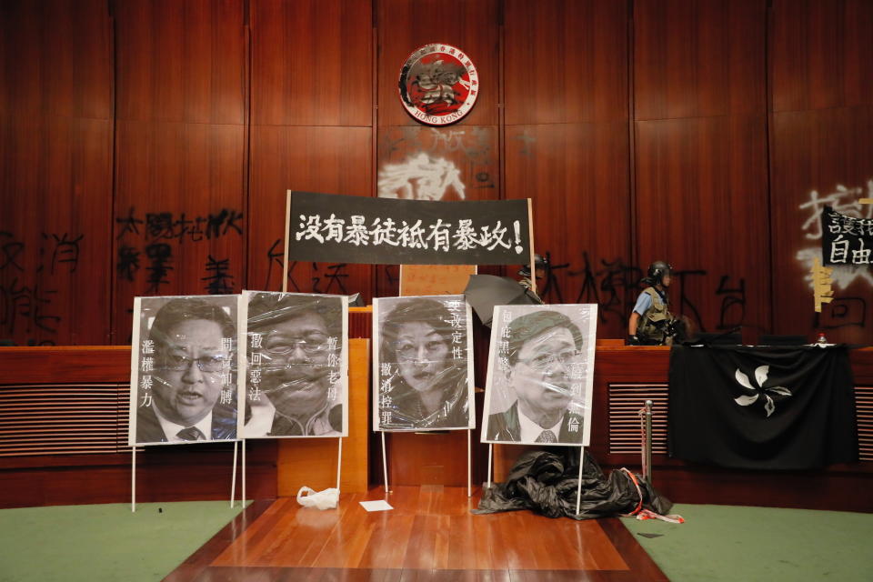 A police officer passes by defaced portraits from left showing, Commissioner of Police Stephen Lo, Hong Kong Chief Executive Carrie Lam, Secretary of Justice Teresa Cheng and Secretary for Security John Lee after authorities take back the meeting hall of the Legislative Council in Hong Kong, during the early hours of Tuesday, July 2, 2019. Hundreds of protesters in Hong Kong swarmed into the legislature's main building Monday night, tearing down portraits of legislative leaders and spray-painting pro-democracy slogans on the walls of the main chamber as frustration over a lack of response from the administration to opposition demands boiled over. (AP Photo/Kin Cheung)