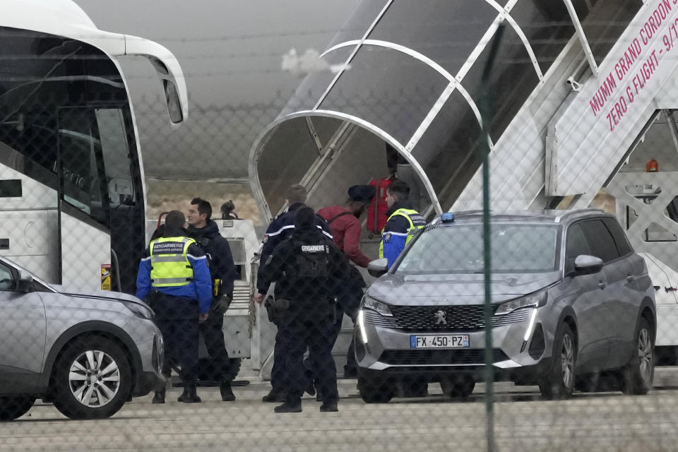 Men board the plane grounded by police at the Vatry airport , Monday, Dec. 25, 2023 in Vatry, eastern France. A charter plane grounded in France for a human trafficking investigation is scheduled to leave Monday for India, after an exceptional holiday ordeal that left some 300 Indians en route for Central America blocked inside a rural French airport for four days. (AP Photo/Christophe Ena)