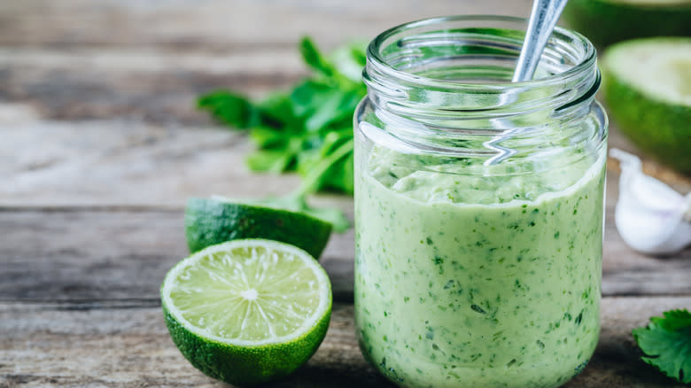 Jar of green dressing next to cut lime 