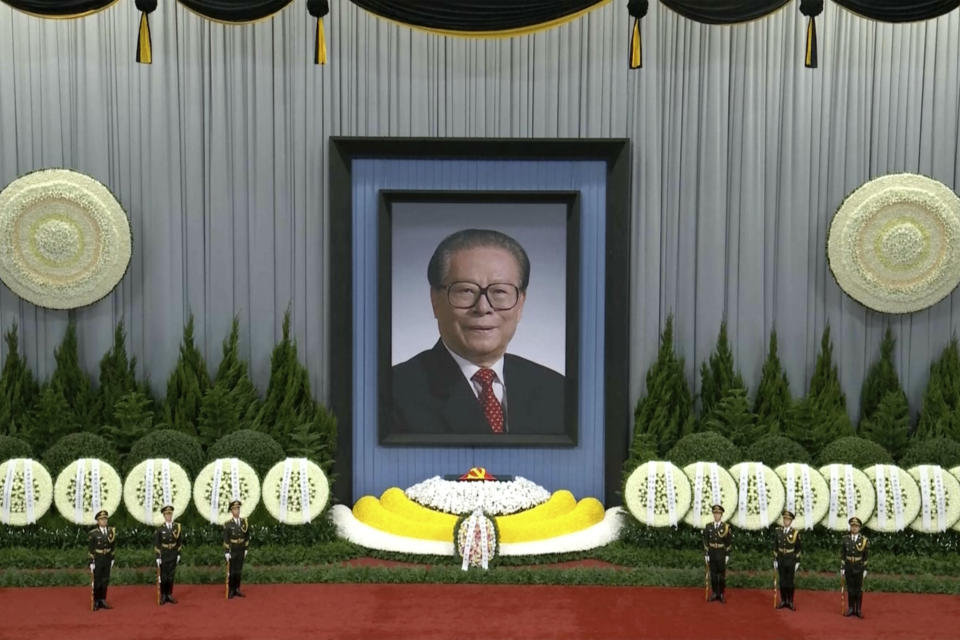 In this image taken from video footage run by China's CCTV, honor guard members stand near a giant portrait of late former Chinese President Jiang Zemin during a formal memorial held at the Great Hall of the People in Beijing on Tuesday, Dec. 6, 2022. (CCTV via AP)