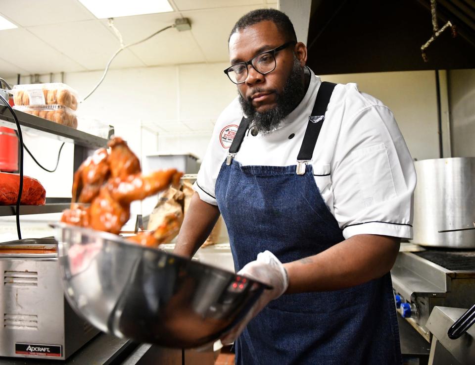 The Wing Kitchen owner Timothy Witcher flips a bowl of chicken wings to get an even coating of Buffalo sauce at his Turnersville restaurant.